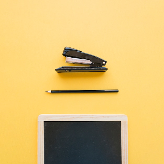 Stapler and pencil near chalkboard