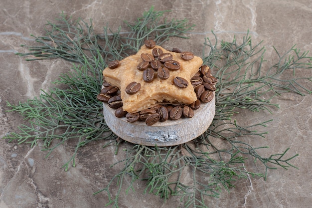 Free Photo star shaped cookie on a pile of coffee beans on a small pedestal on marble. 