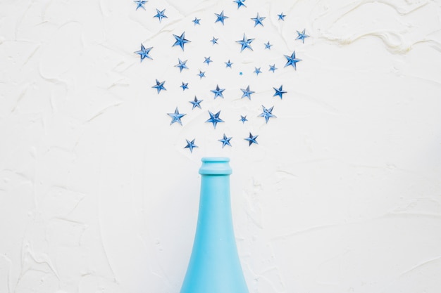 Free photo star spangles scattered from blue bottle on table