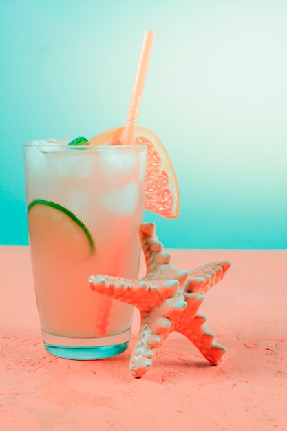 Free Photo starfish near the grapefruit cocktail on coral desk against teal background