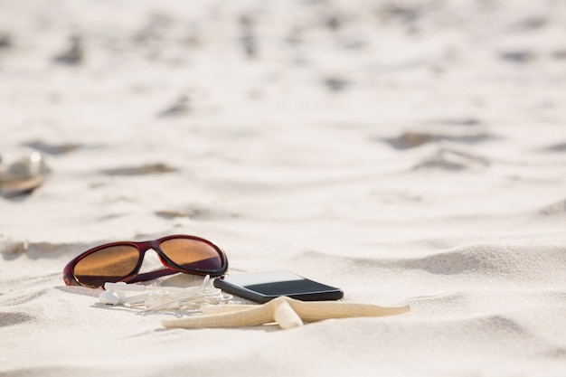 Free photo starfish, sunglasses, headphones and mobile phone kept on sand