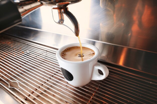 Start your day with cup of aromatic drink. Stylish black espresso making machine brewing coffee, shooted in cafe.