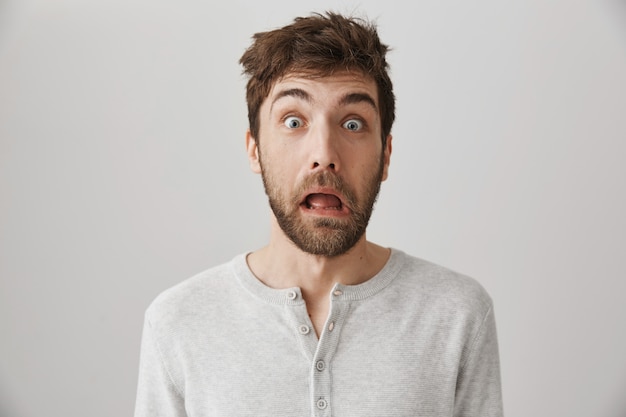 Startled caucasian guy waking up morning, grimacing with tossed messy hair