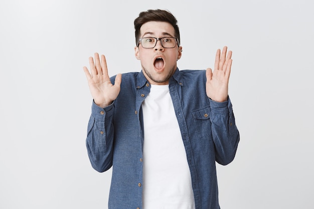 Startled worried guy raise hands up in surrender and gasping shocked