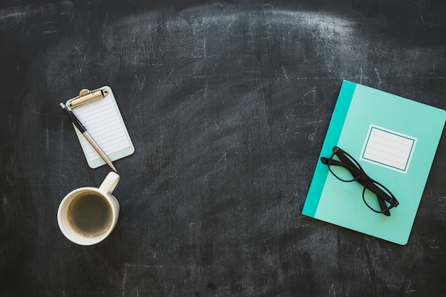 Stationeries and coffee cup on blackboard