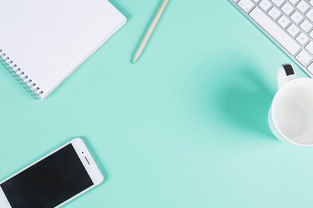 Stationeries with keyboard; cup and cell phone on colored background