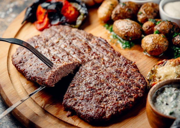 Free photo steak with fried potatoes and vegetables on wooden board