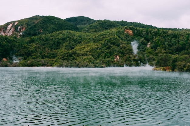 Free Photo steam coming out of a beautiful body of water surrounded by green mountains