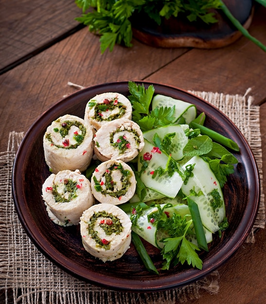 Free Photo steamed chicken rolls with greens and fresh vegetable salad on a brown plate