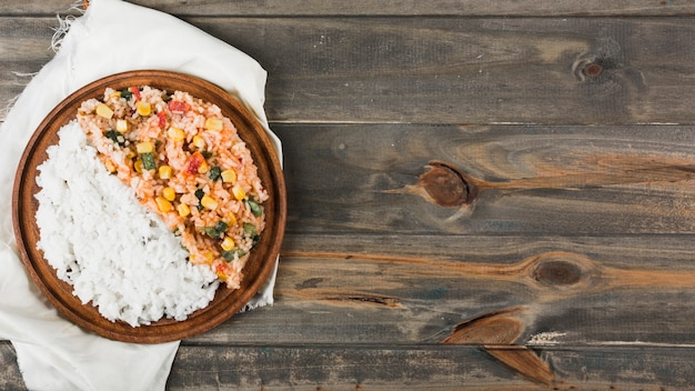 Free photo steamed rice and fried rice on wooden plate over the white napkin on wooden table