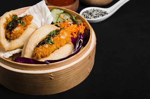 Steamed sandwich in bamboo steamer with salad on black background