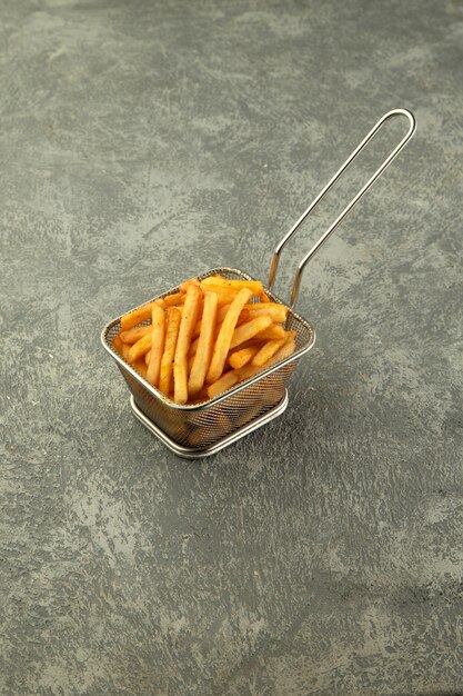 Steel basket of french fries on plain grey background