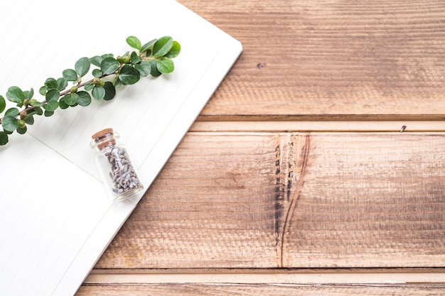 Free Photo stem and lavender flower bottle on notebook over the wooden backdrop