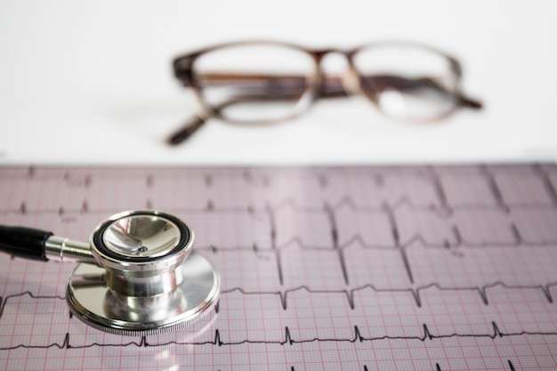 Free photo stethoscope on cardiogram with eyeglasses