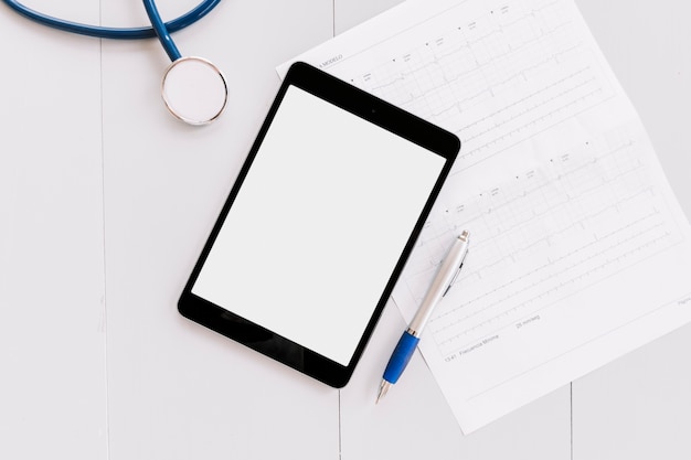 Free photo stethoscope; digital tablet; pen and cardiogram chart on white wooden surface