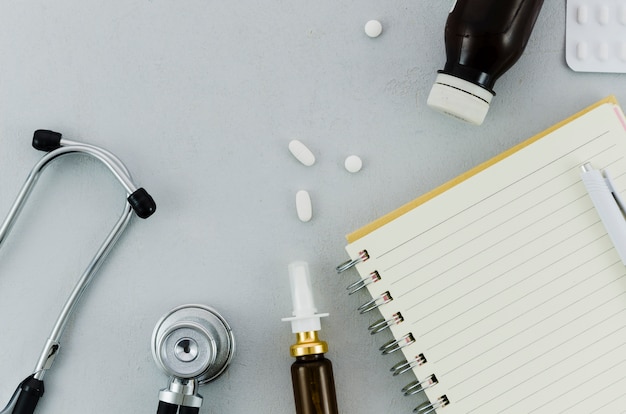 Free photo stethoscope; pills; bottle; nasal spray; diary and pen on grey background