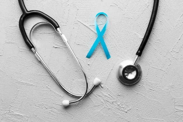 Stethoscope and teal ribbon on plaster background