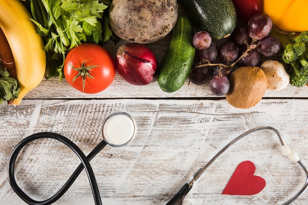 Free Photo stethoscope with heart shape near fresh vegetables on wooden background