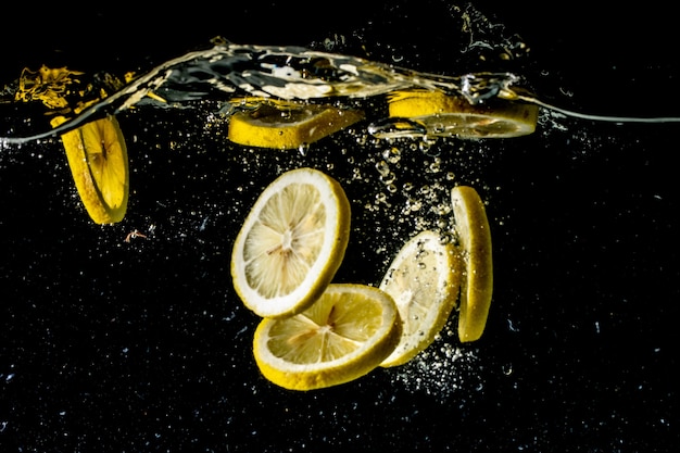 Still life photography shot of lemon slices falling under the water and making a big splash