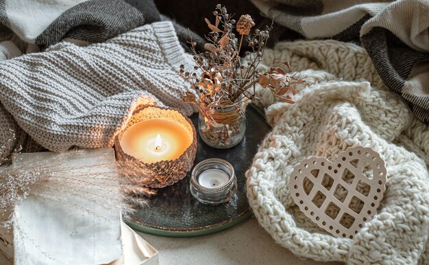 Still life with candles in candlesticks, decor details and knitted items.