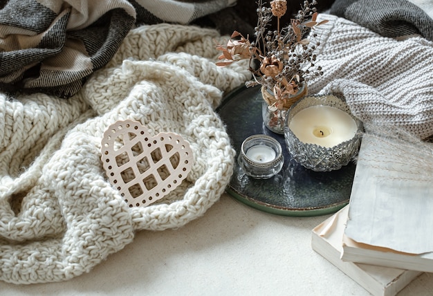 Still life with a decorative heart, books and candles in candlesticks. The concept of Valentine's day and home decor.