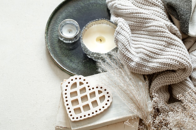 Free photo still life with a decorative heart, books and candles in candlesticks. the concept of valentine's day and home decor.