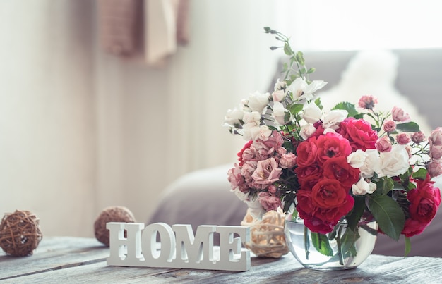 Still-life with an inscription house and a vase with flowers of different roses. The concept of home comfort and decor.