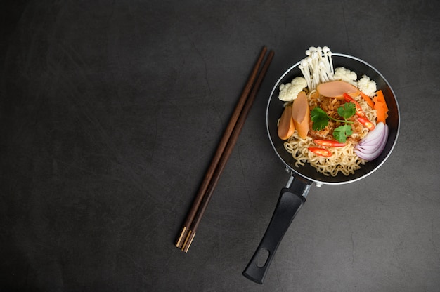 Free Photo still life with noodles in a pan and chopsticks.