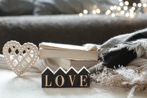 Free photo still life with wooden word love, books and cozy items on a blurred background with boke.