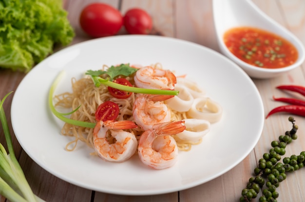 Stir-fried instant noodle with prawn and crab stick along  in a white dish.