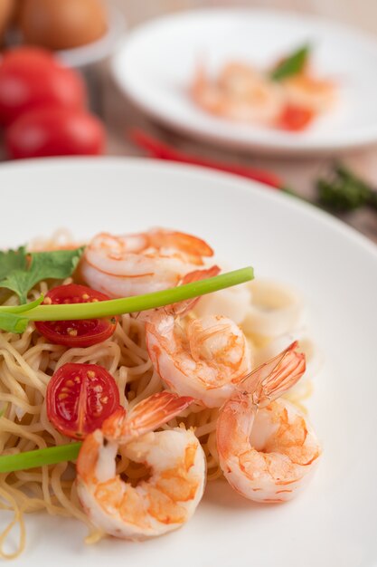 Stir-fried instant noodle with prawn and crab stick along  in a white dish.