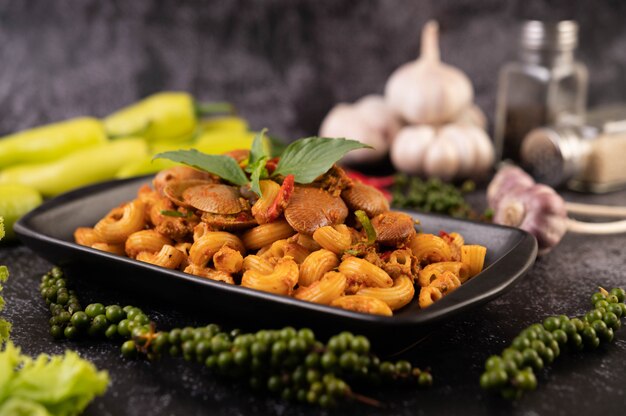 Stir-fried macaroni with clams on a black plate.