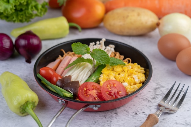 Stir fried noodle that combines corn, golden needle mushroom, tomato, sausage, edamame and spring onions in a frying pan.