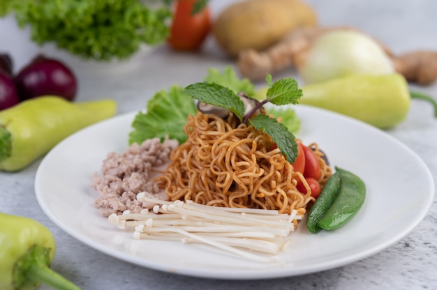 Stir-fried noodles with minced pork, edamame, tomatoes and mushrooms in a white plate.