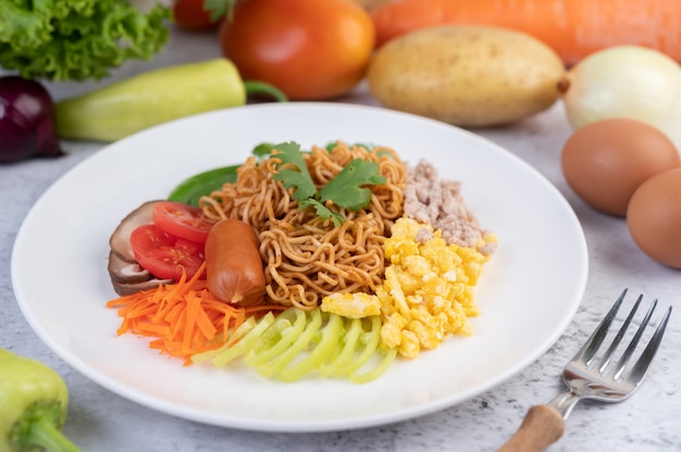 Free photo stir-fried noodles with minced pork, edamame, tomatoes and mushrooms in a white plate.