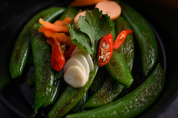 Stir-fried peas in a frying pan on black cement surface.