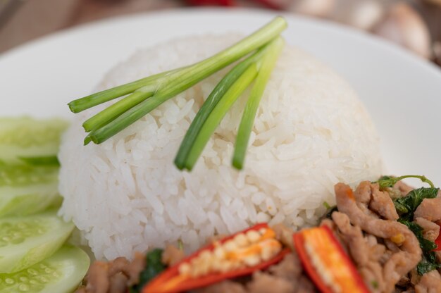 Stir fried pork with basil, fried egg in a white dish .