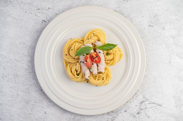 Free photo stir-fried spaghetti and pork, beautifully arranged in a white plate.