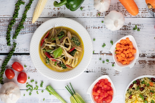 Free photo stir fried spicy squid in the white plate with spices on a white wooden floor.