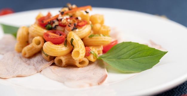 Stir-fry macaroni on top pork roughly in a white plate.