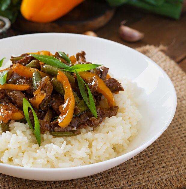 Stir frying beef with sweet peppers, green beans and rice