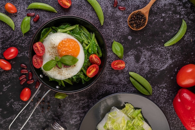 Free photo stir kale and fried egg in a pan.