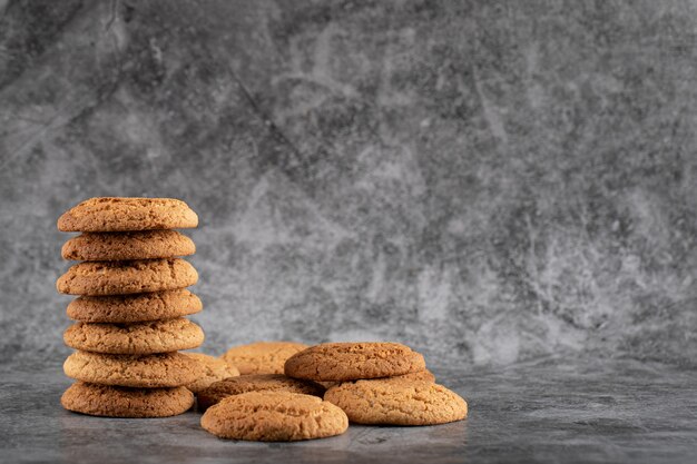 A stock of oatmeal cookies on grey concrete.