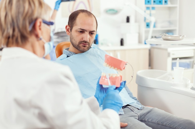 Free photo stomatologist explaining proper dental hygiene using teeth skeleton during stomatology appointment