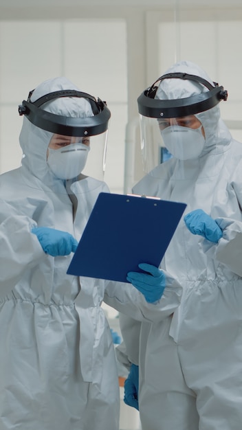 Free Photo stomatology specialists talking about patient teeth healthcare while wearing protection suit against covid virus. team of dentists with face shield discussing dental operation at clinic