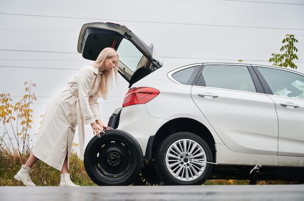 Stopped white car with punctured car tire on a roadside