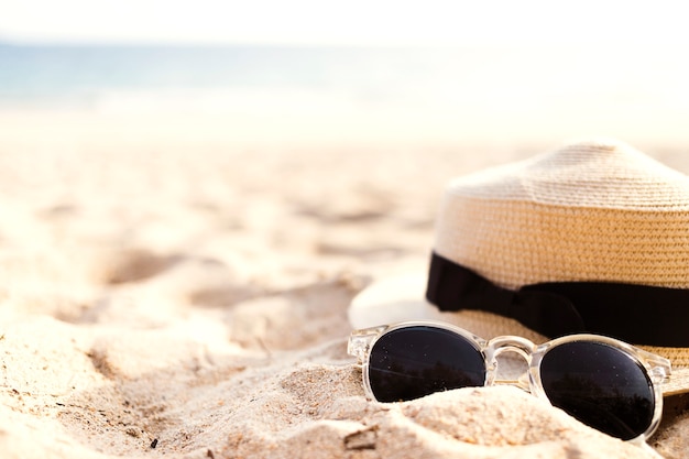 Straw hat and sunglasses on sand near the coast