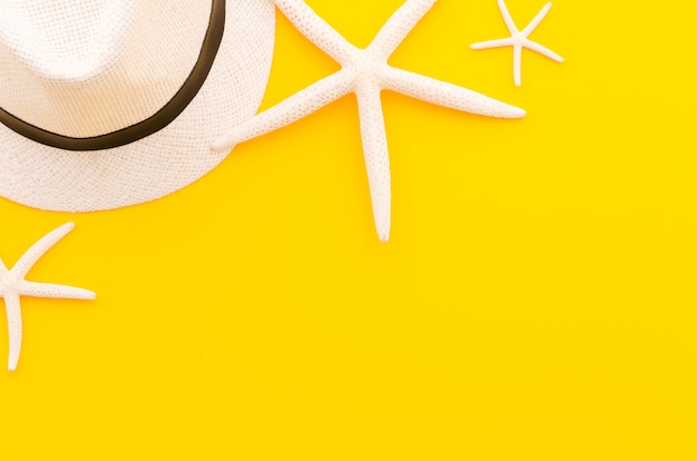 Free photo straw hat with sea stars on yellow table