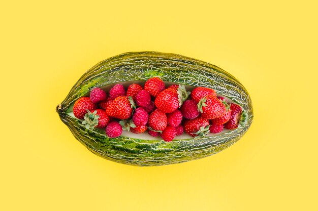 Strawberries inside the green netted melon on yellow background