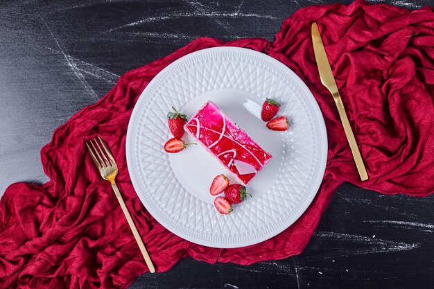 Strawberry cake with golden cutlery on white plate. 